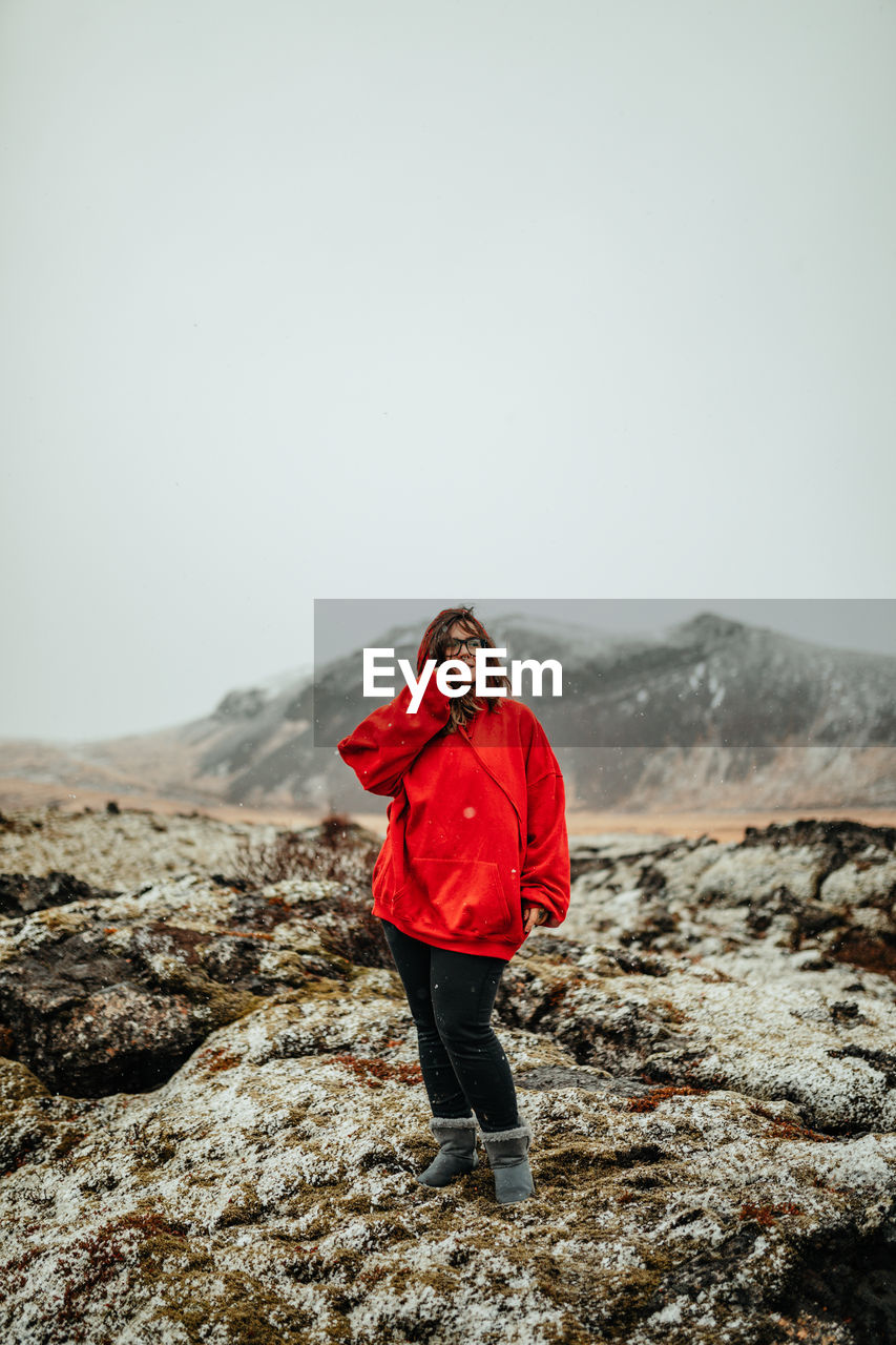 Young happy tourist in eyeglasses with piercing looking away between deserted ground in snow