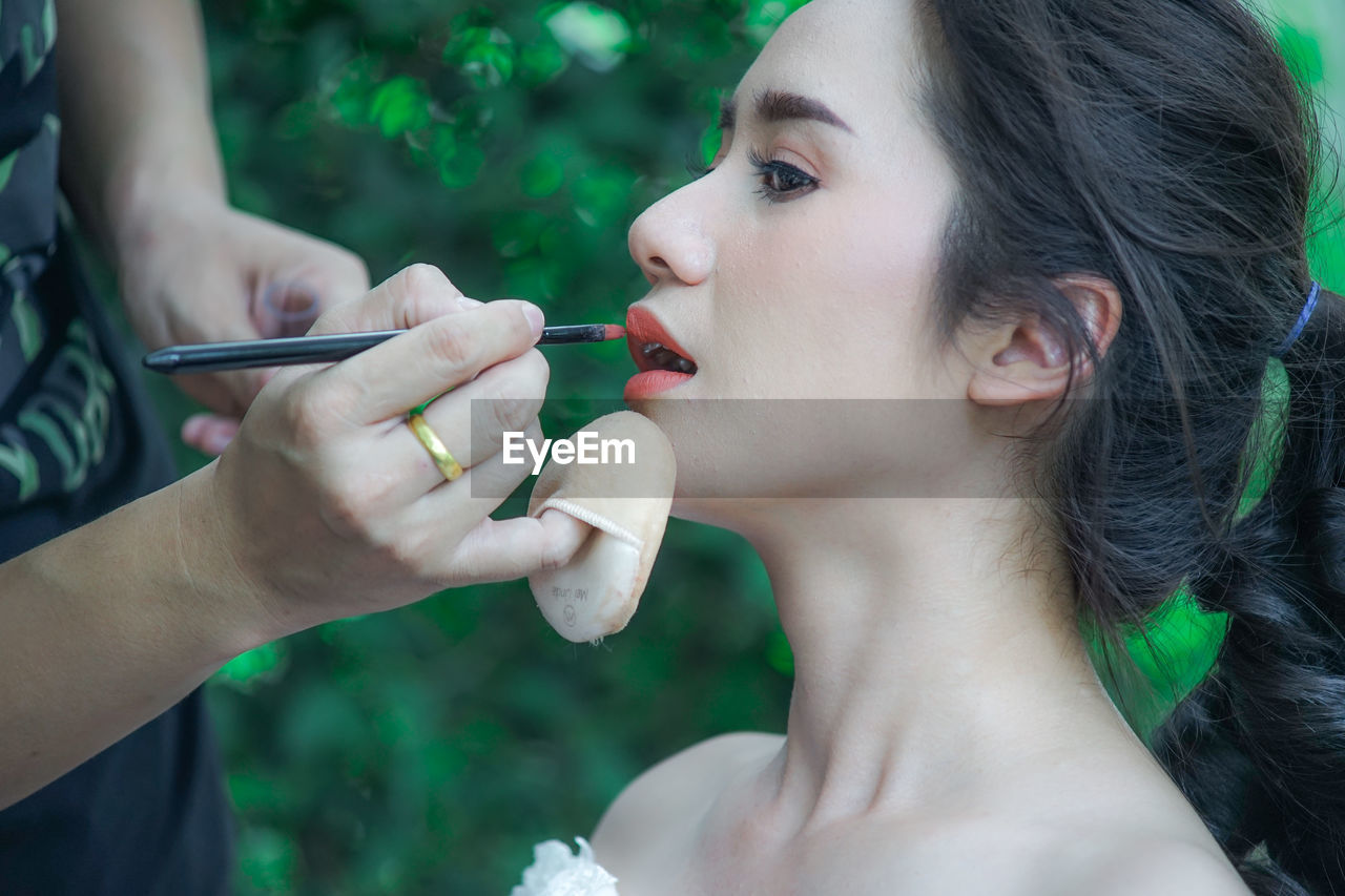Close-up of person applying make-up on woman face