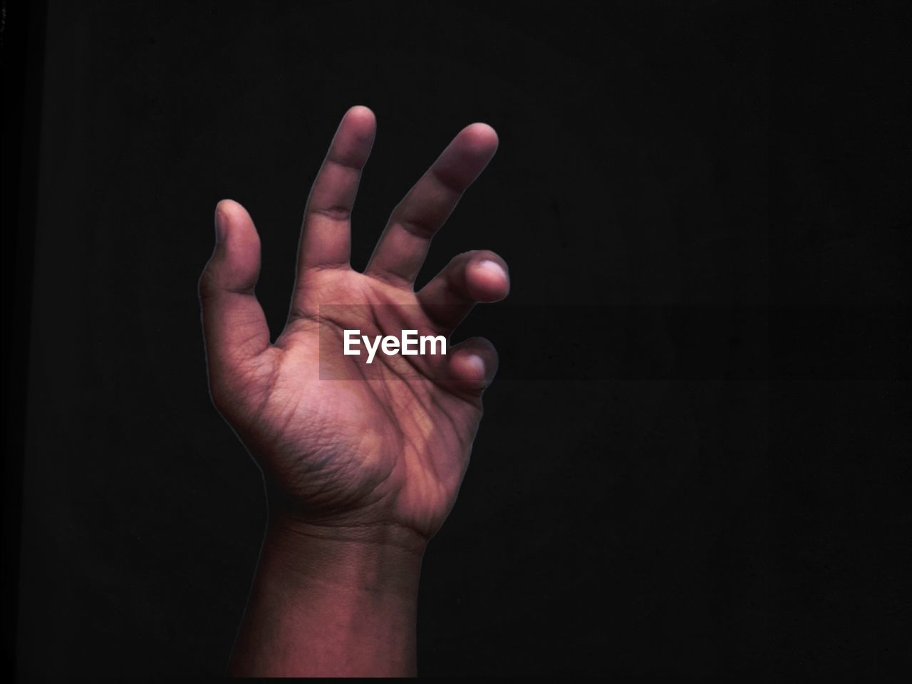 CLOSE-UP OF PERSON HAND AGAINST BLACK BACKGROUND