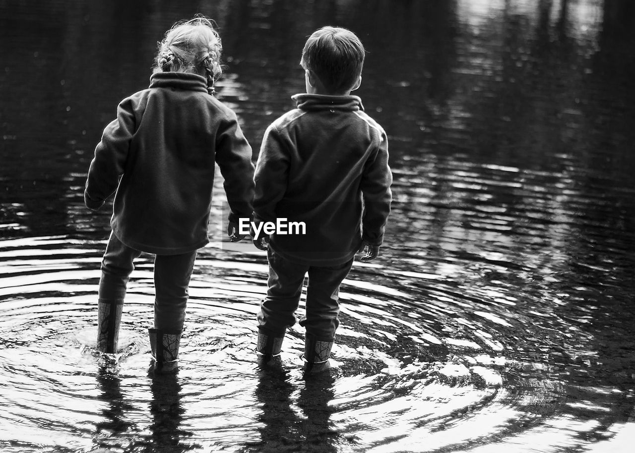Siblings wading in lake