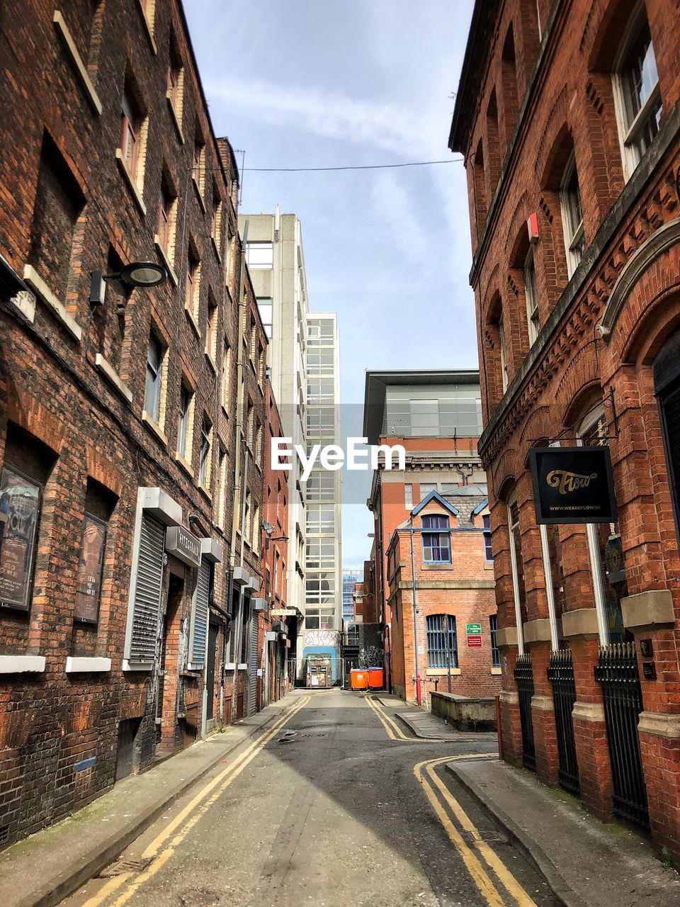 EMPTY ROAD BY BUILDINGS IN CITY