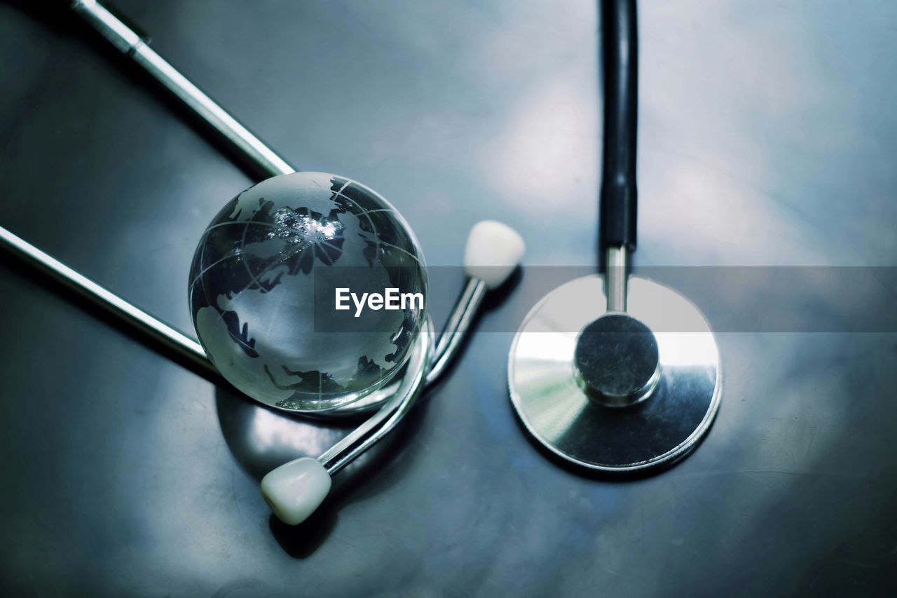 High angle view of stethoscope and crystal ball on table