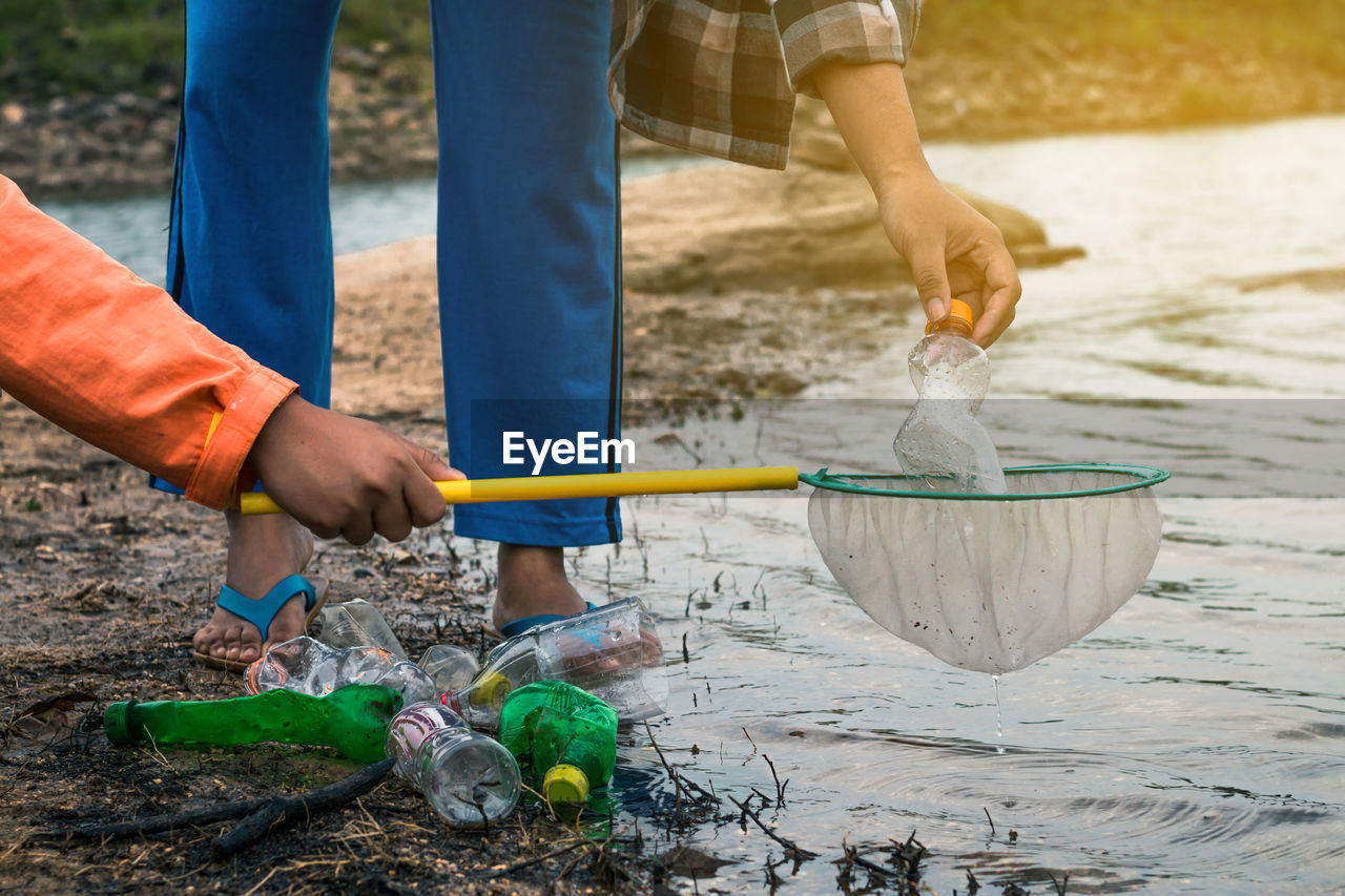 Low section of volunteers removing plastic bottles from lake