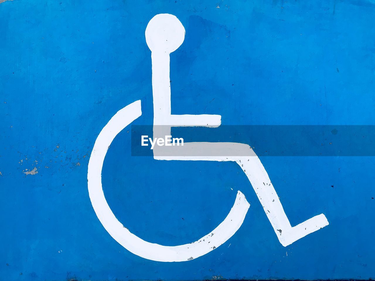 Close-up of white disabled sign on blue wall