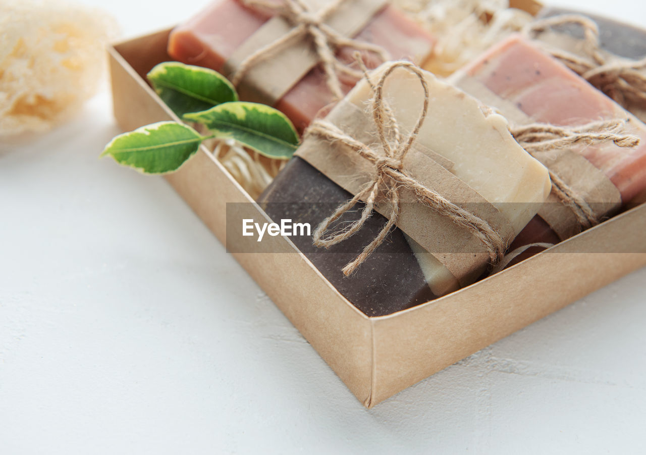 Assorted handmade soap bars and green leaves in box on straw