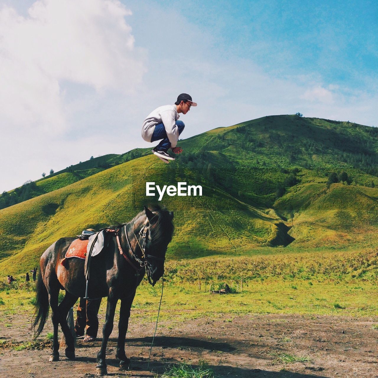 Side view of man jumping in mid air against green mountains