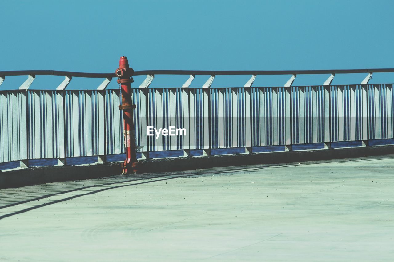 Low angle view of railing against clear blue sky