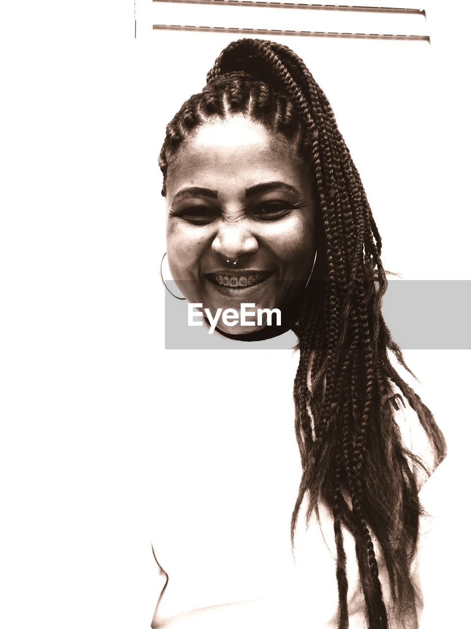 PORTRAIT OF SMILING YOUNG WOMAN AGAINST WHITE BACKGROUND