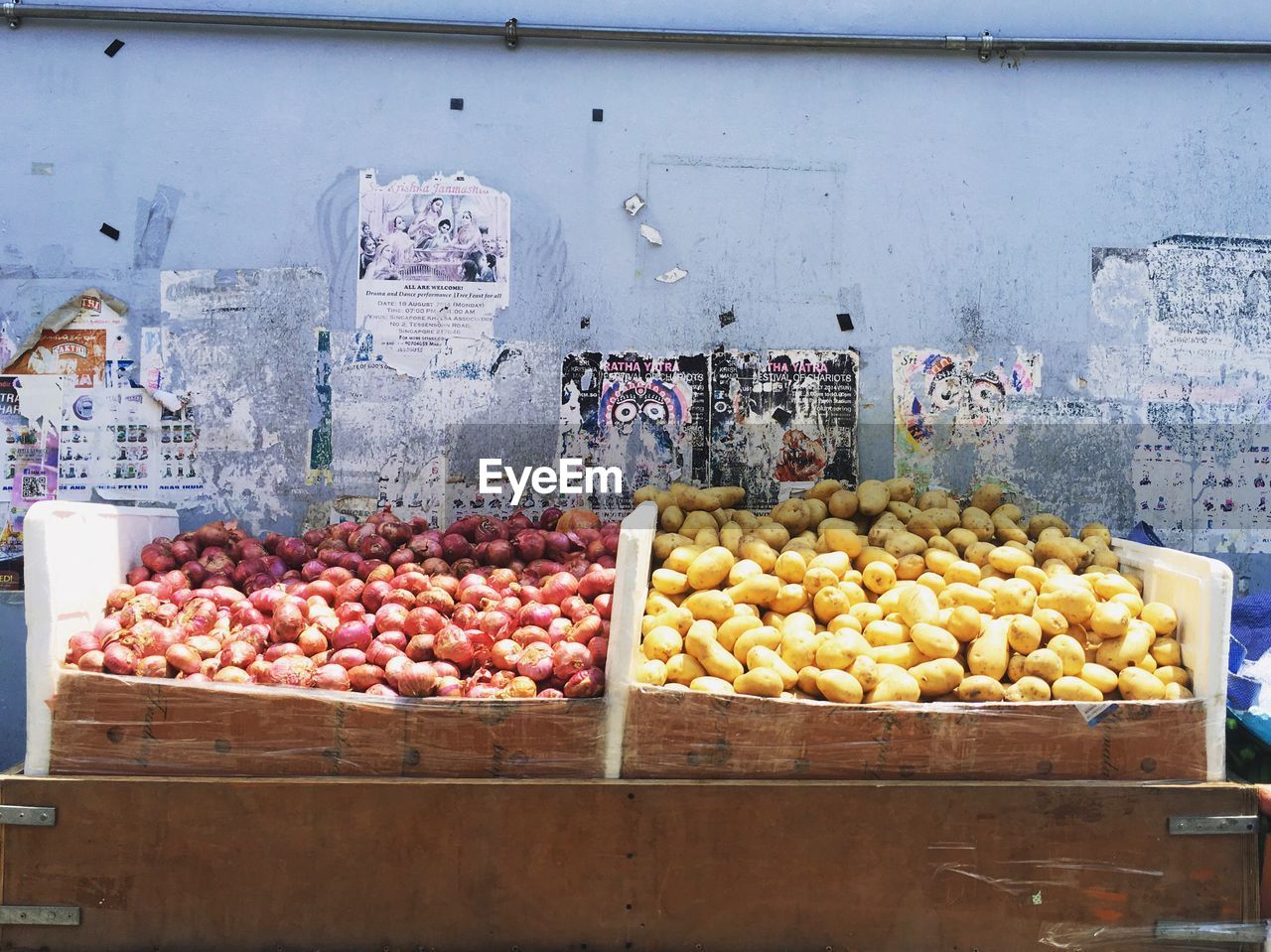 Onions and potatoes at market stall against wall