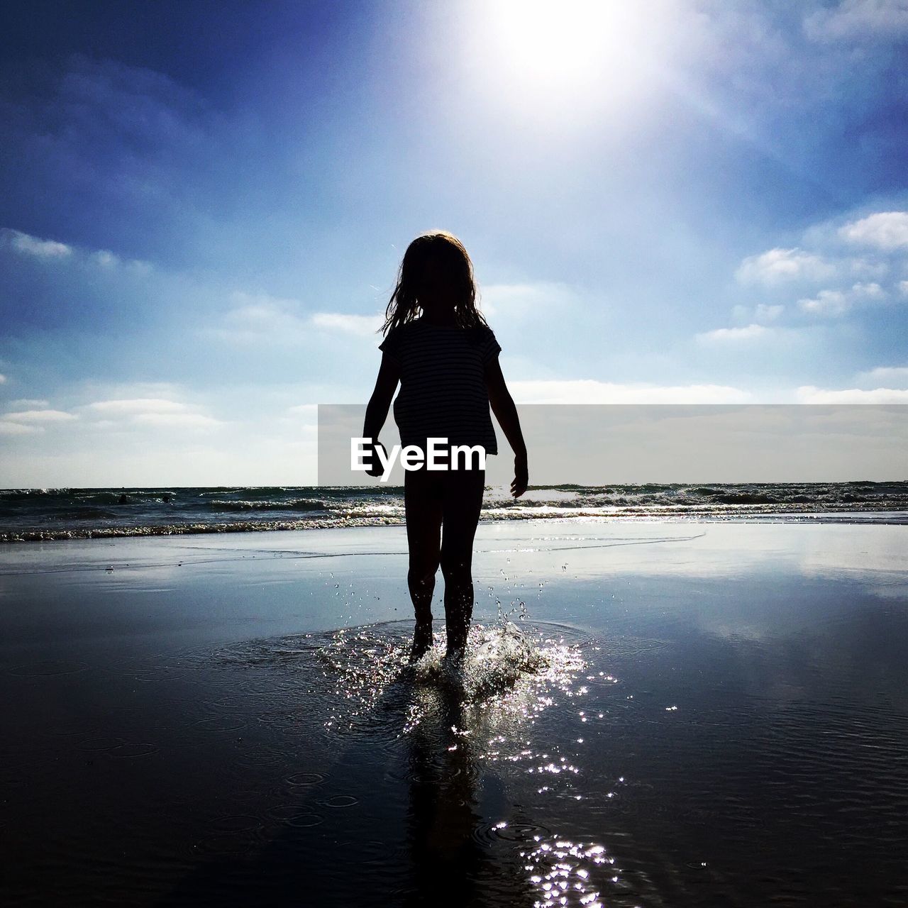 Silhouette girl at beach against sky during sunny day