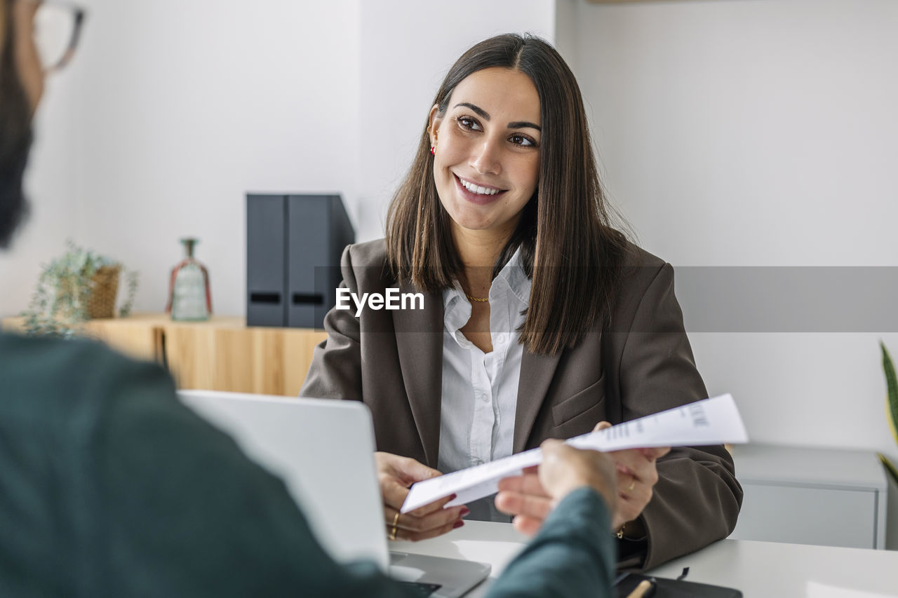 Candidate giving resume to recruiter at desk in workplace