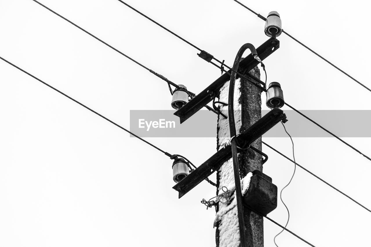 Low angle view of electricity pylon against clear sky