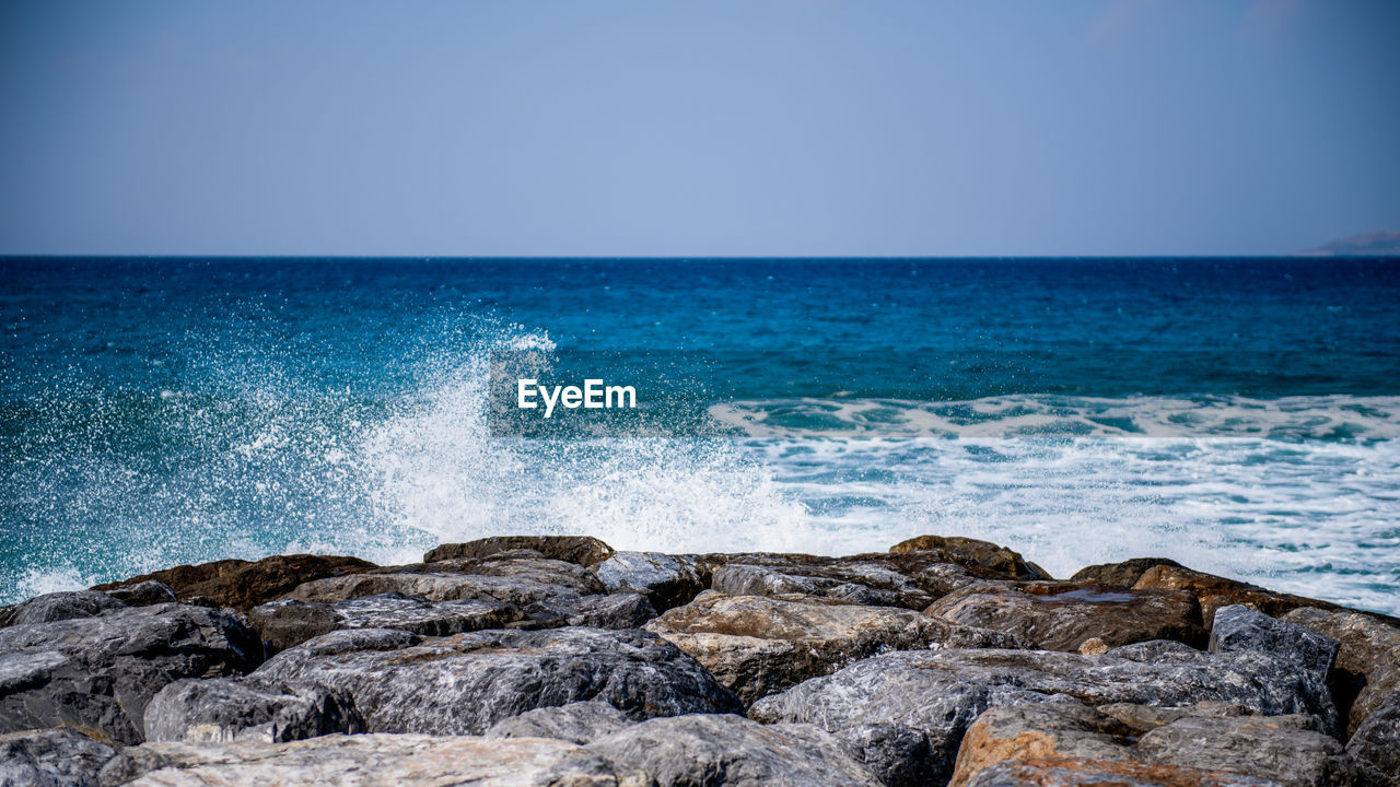 SCENIC VIEW OF ROCKY BEACH AGAINST CLEAR BLUE SKY