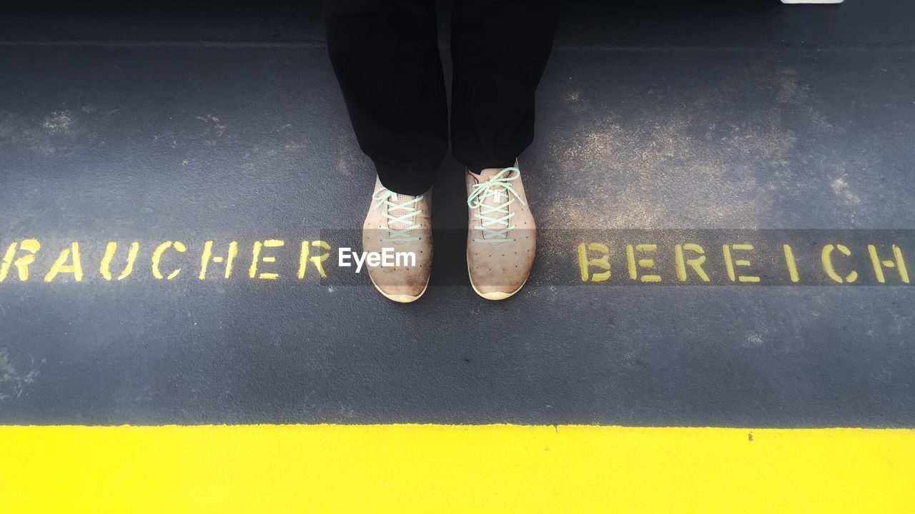 Low section of person standing amidst text on street