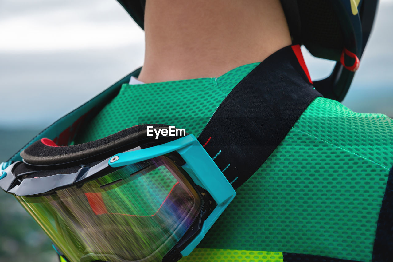 Close-up of protective goggles mask on the neck of a young cyclist rider outdoors. view from the