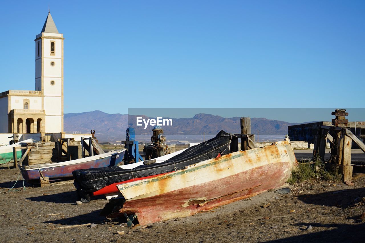 Abandoned ship on beach against clear blue sky