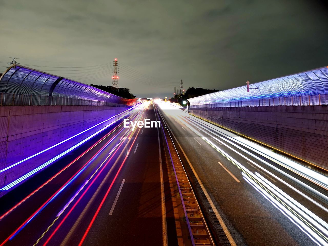 Light trails on road in city against sky at night