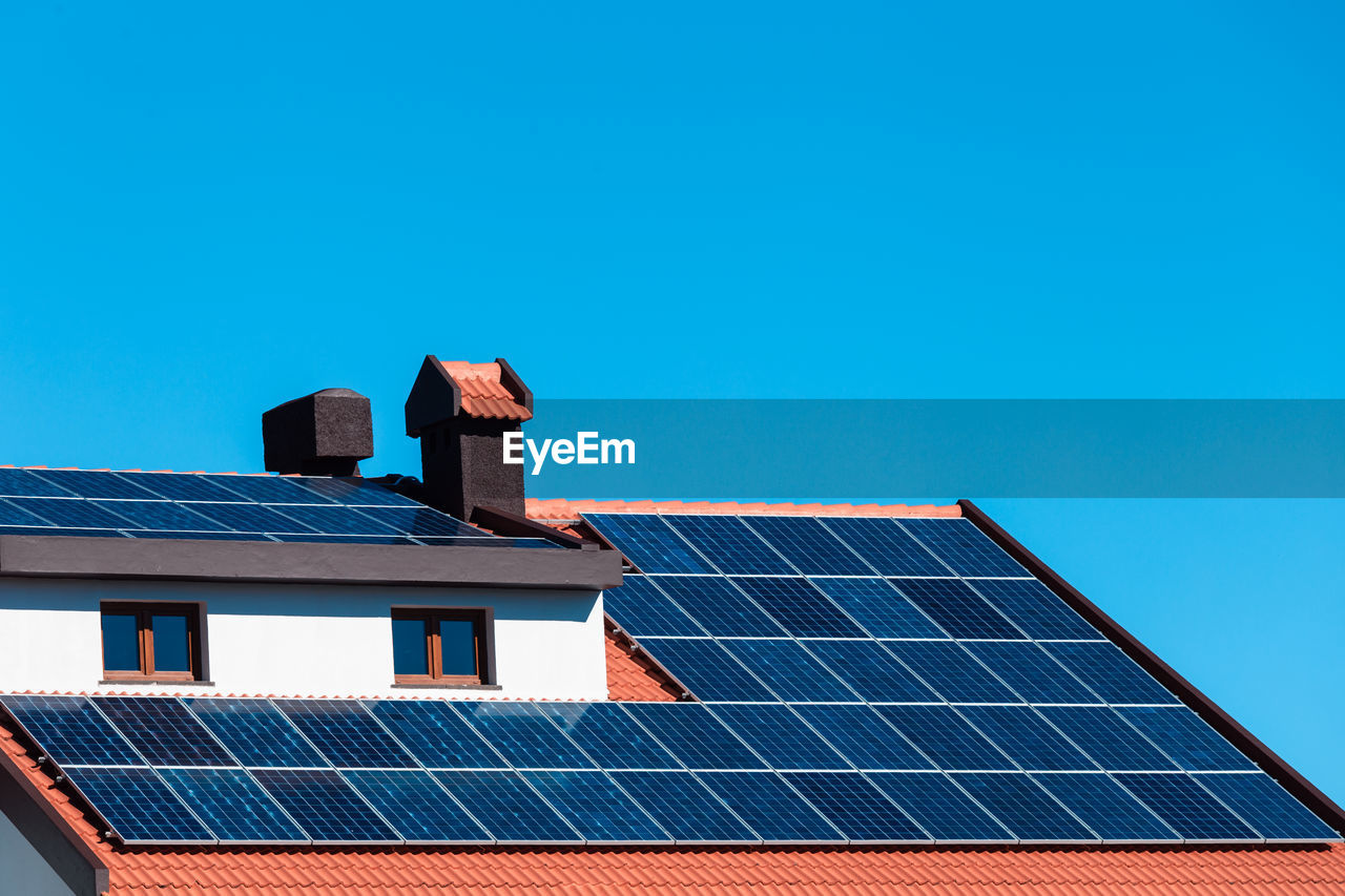 Low angle view of solar panel on house roof against blue sky