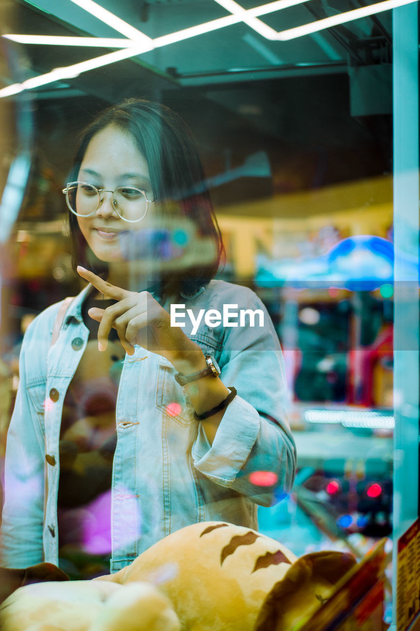 Portrait of young woman in store window