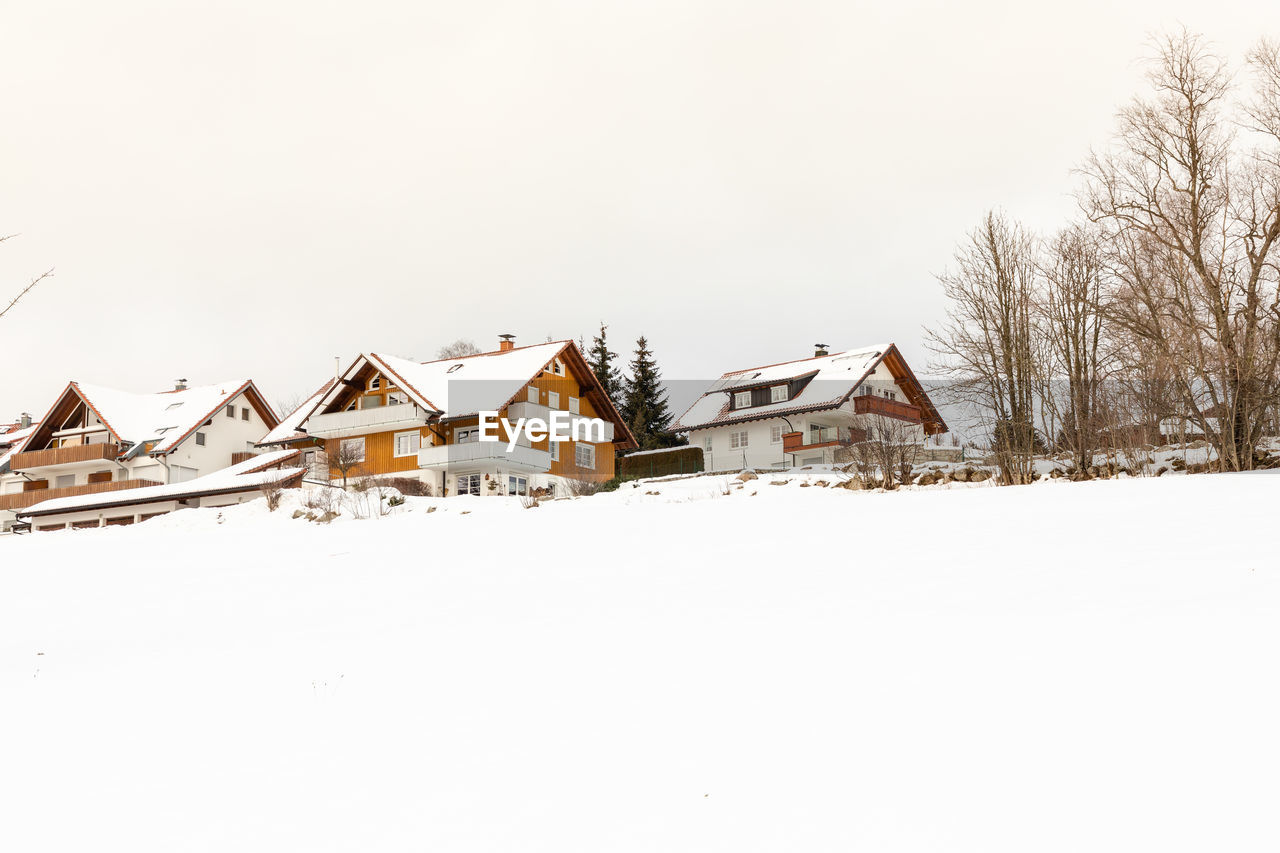 Houses on snow covered land against clear sky