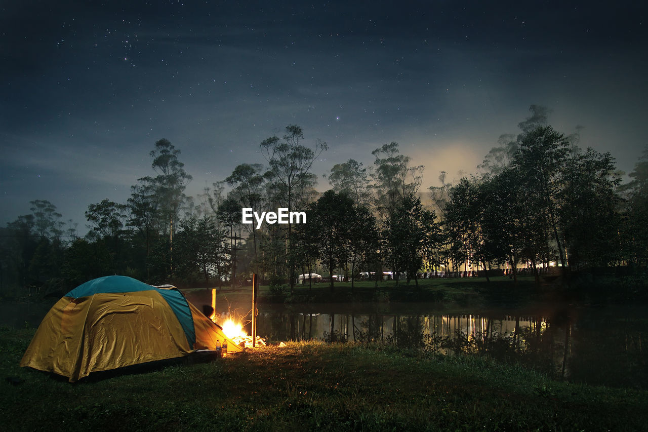 Camping tent by lake at dusk