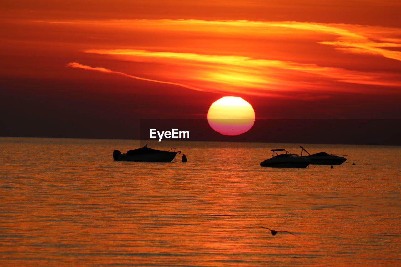 Silhouette boat in sea against orange sky