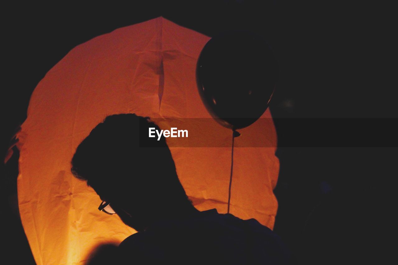 Silhouette man with paper lantern at night