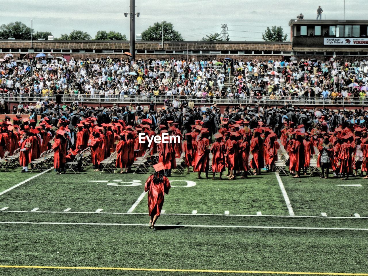 Students in graduation gowns during ceremony at stadium