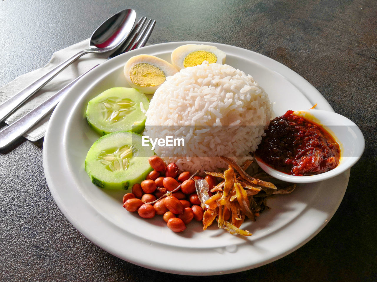 Malaysia famous nasi lemak served with fried anchovies, nuts, cucumbers and boiled egg. 