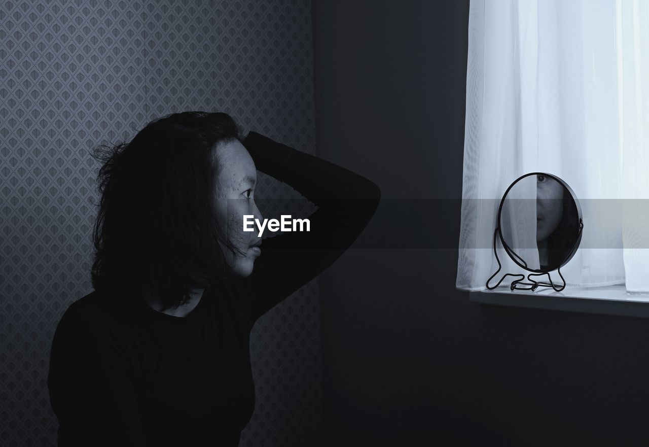 Woman with reflection in mirror sitting at home