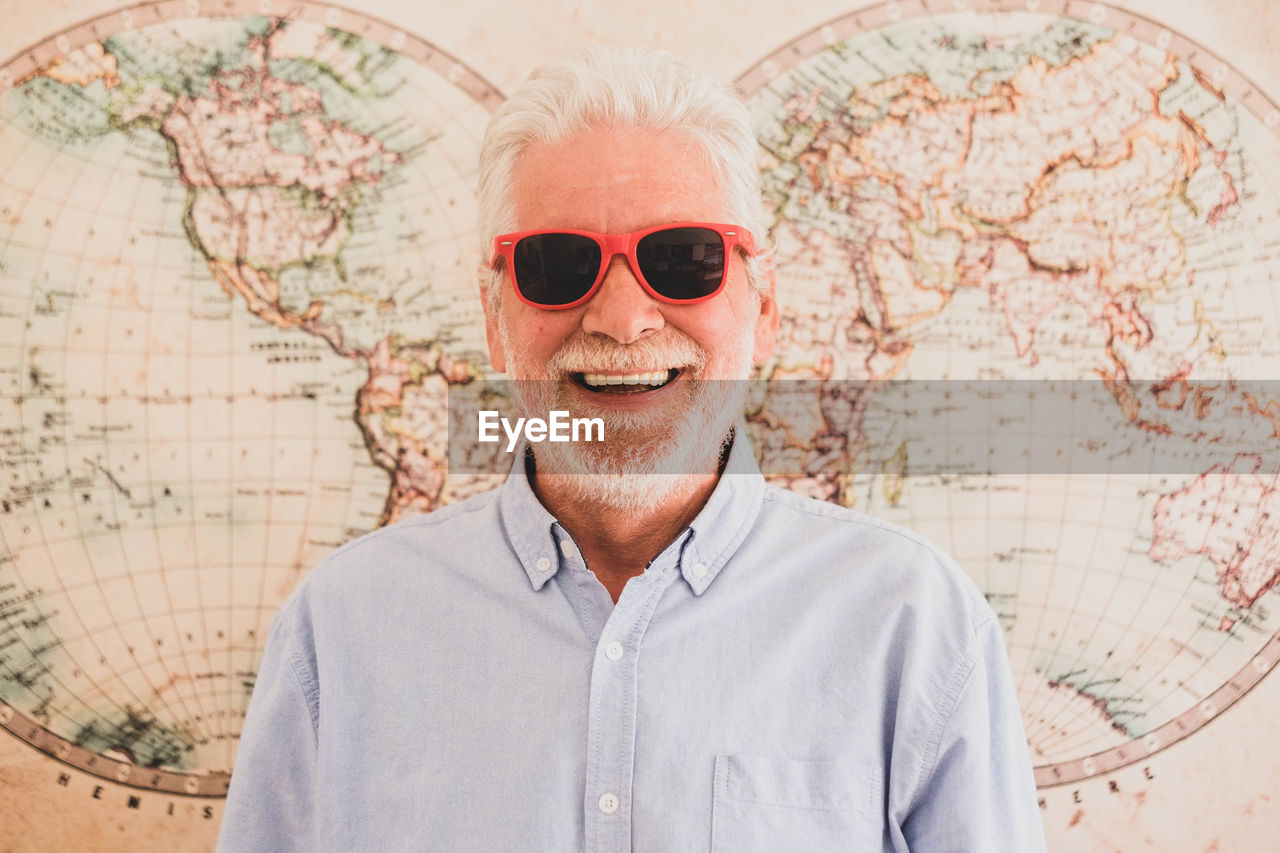 PORTRAIT OF MAN WEARING SUNGLASSES STANDING AGAINST WALL