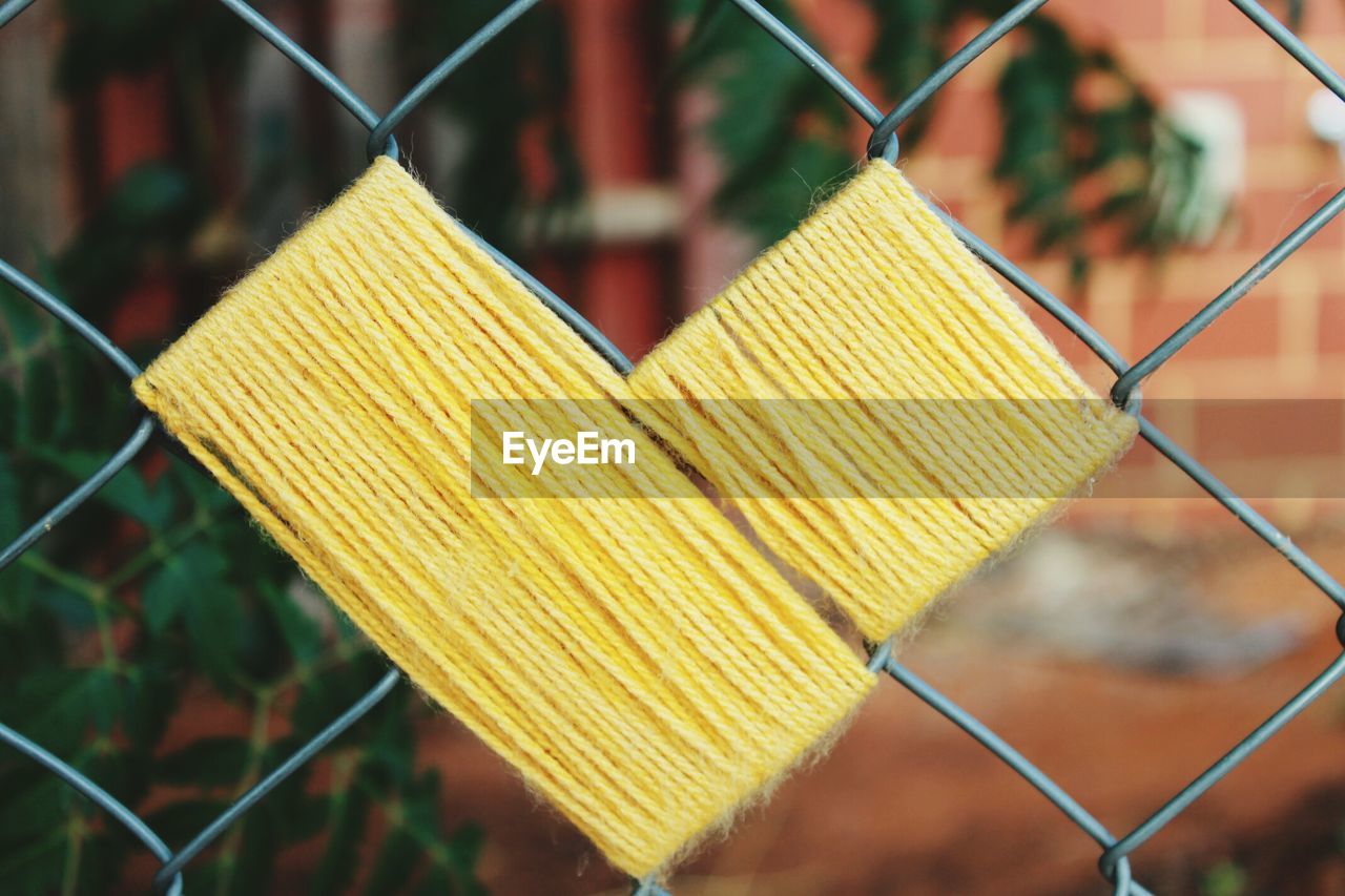 Close-up of heart shaped wool on chainlink fence