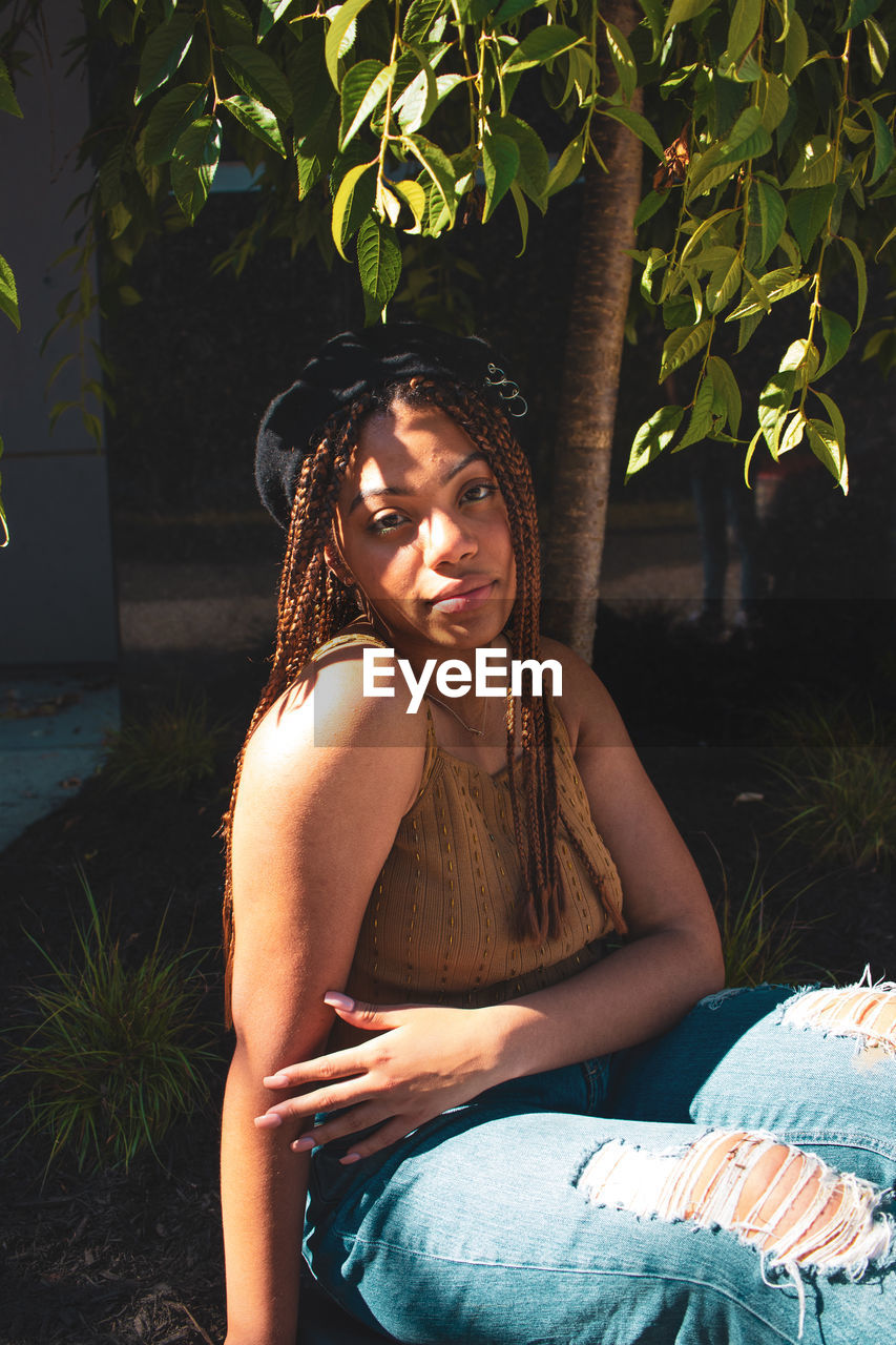 PORTRAIT OF BEAUTIFUL YOUNG WOMAN SITTING IN PLANT