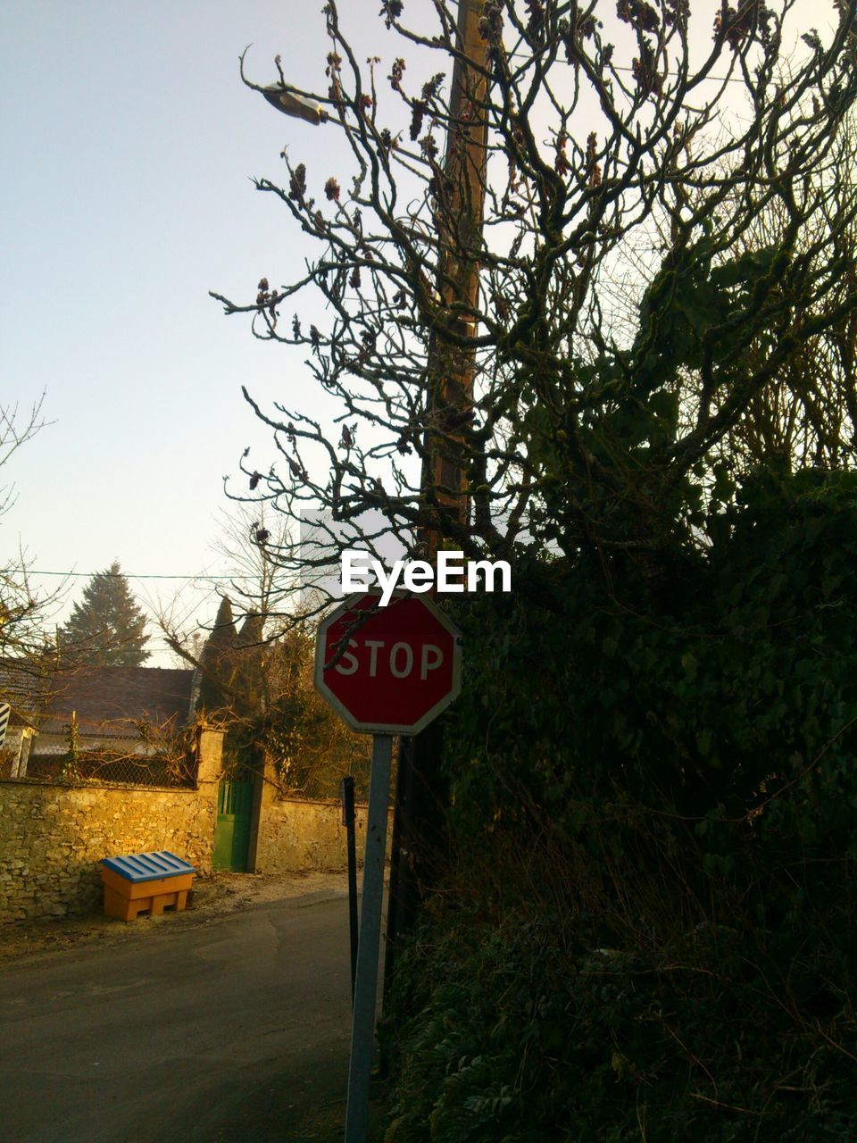 Stop sign by road against sky