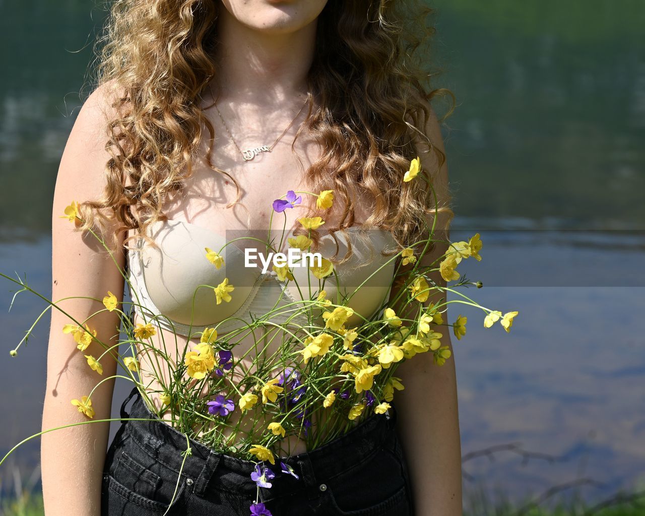 Midsection of woman standing by flowering plants