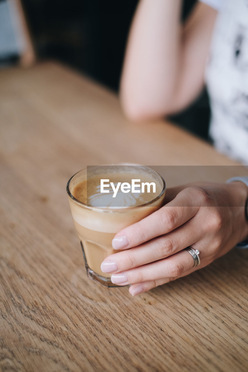 Midsection of woman holding coffee cup on table