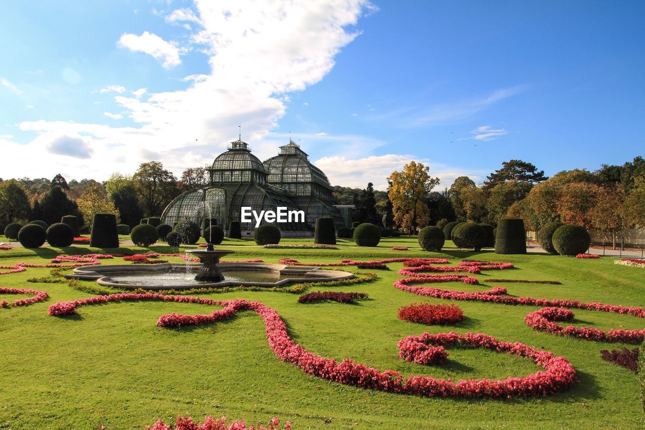 Fountain in botanical garden and greenhouse on background