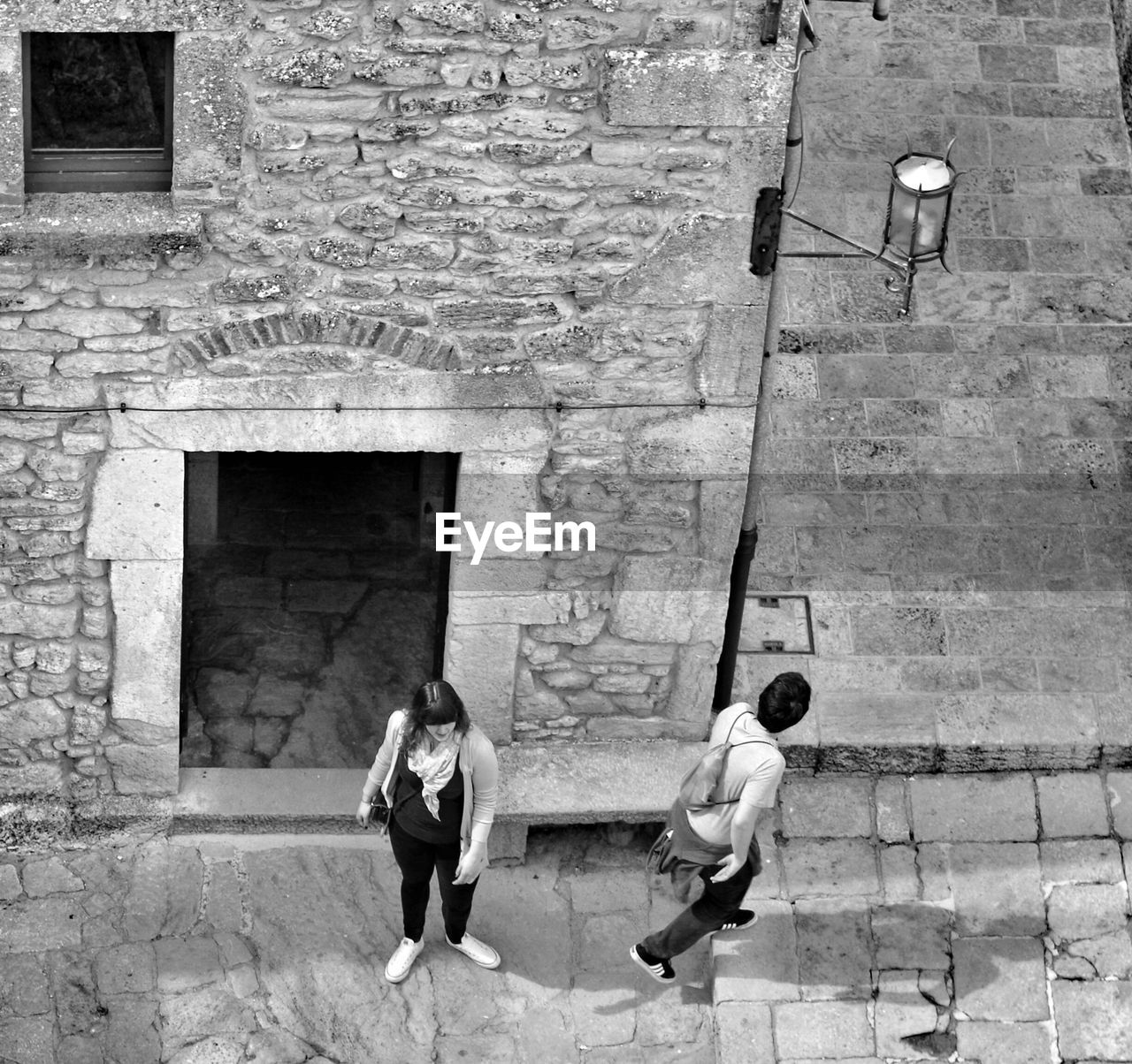 High angle view of two people walking along stone wall