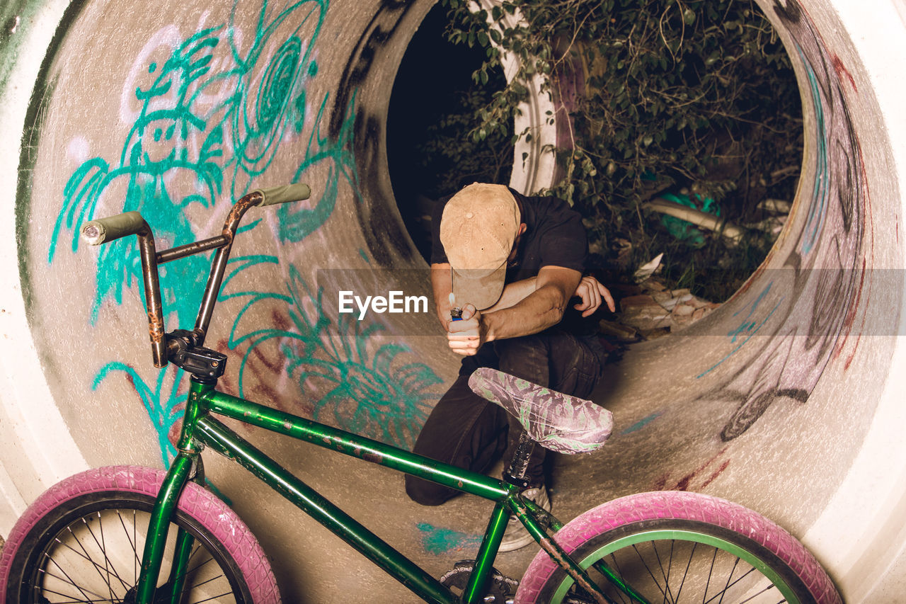 WOMAN HOLDING BICYCLE AGAINST WALL