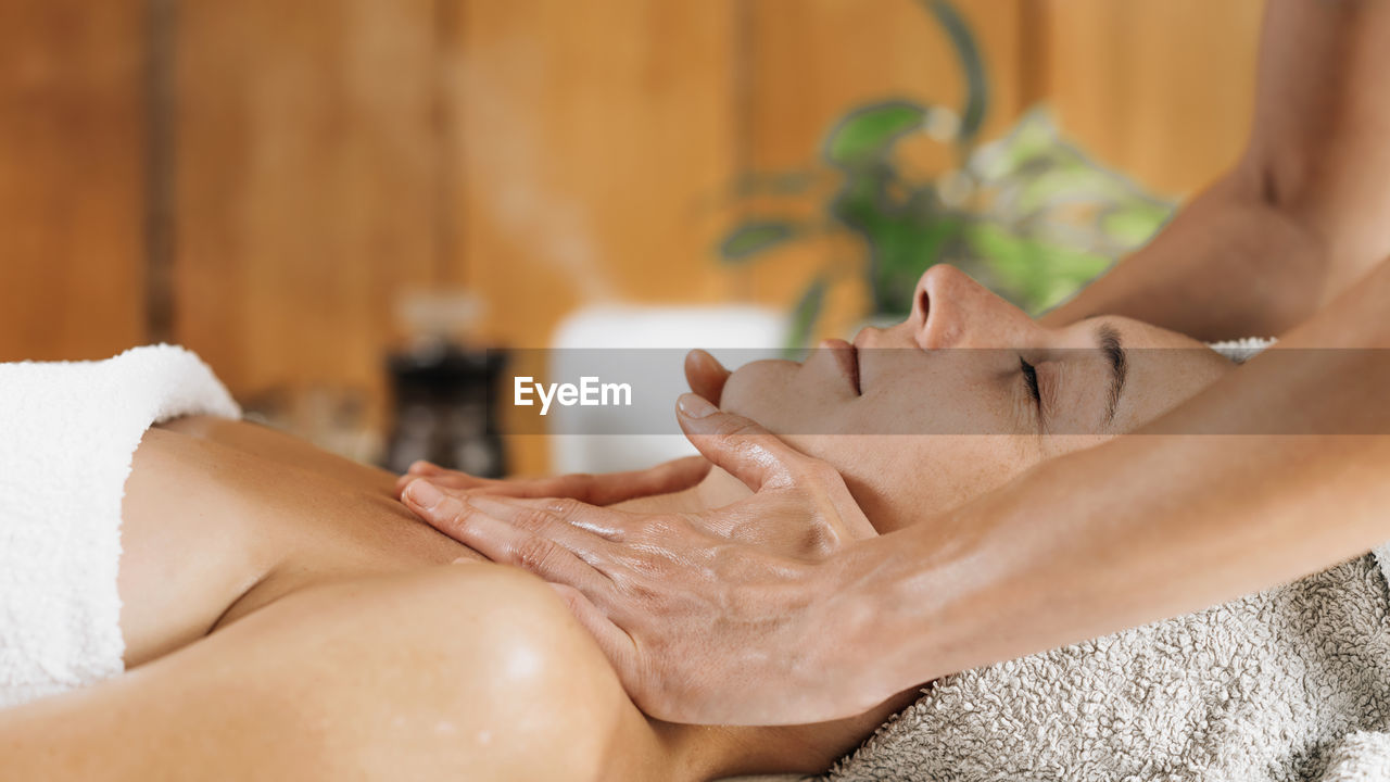 Woman enjoying professional ayurveda neck and shoulders massage with ethereal oil