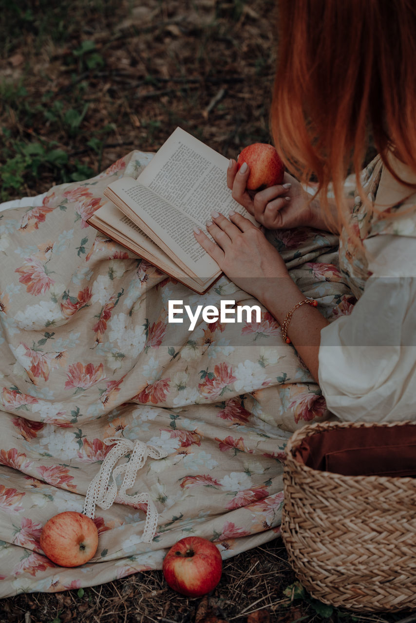 Redhead woman holding an apple and reading book