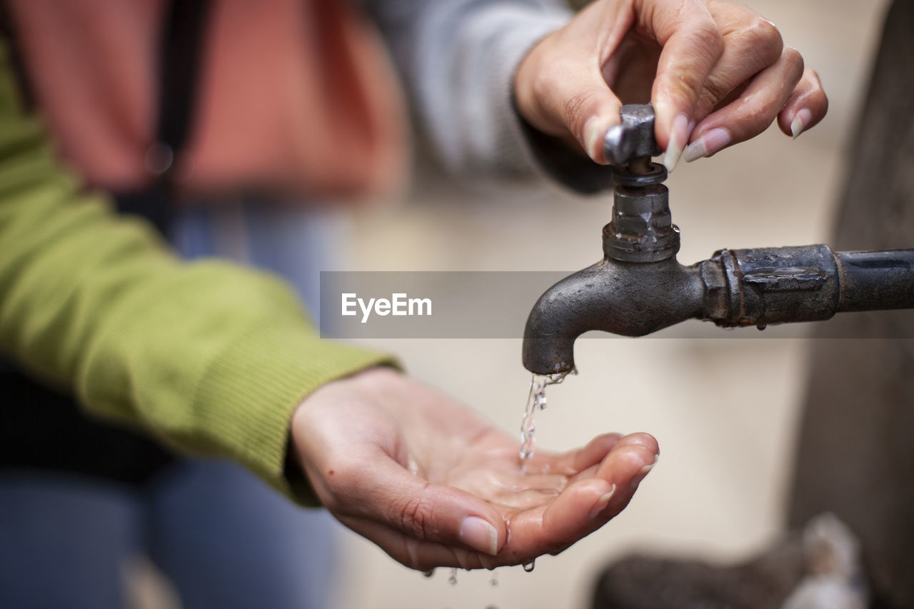 Midsection of woman washing hands under tap