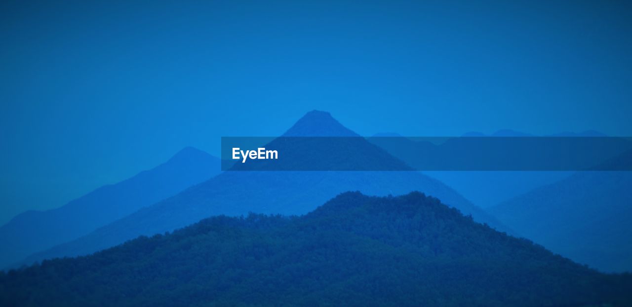 Scenic view of mountain range against blue sky