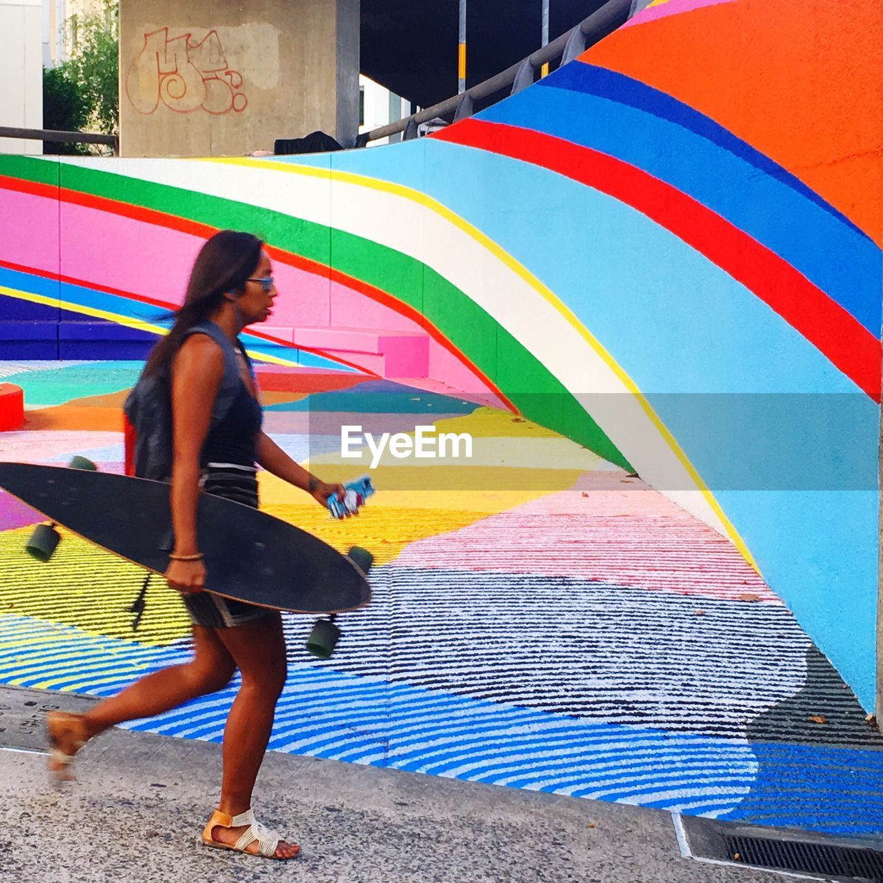 Side view of women walking with skateboard in hand