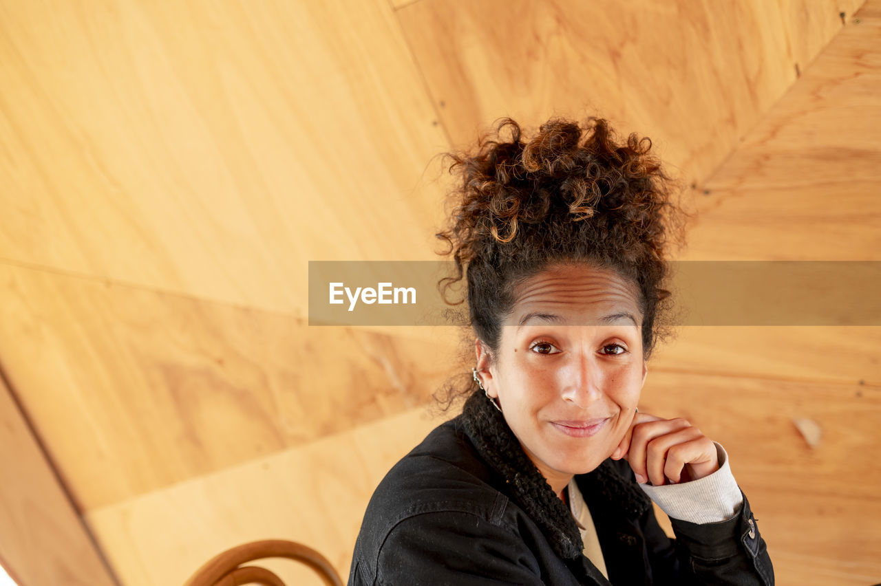 Happy latin woman smiling while sitting indoors.