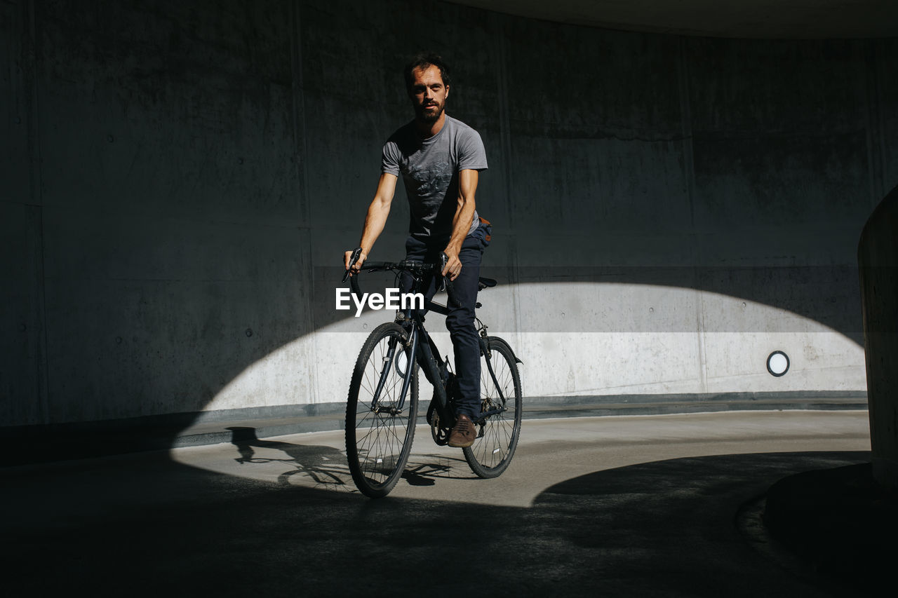 FULL LENGTH OF MAN RIDING BICYCLE ON STREET