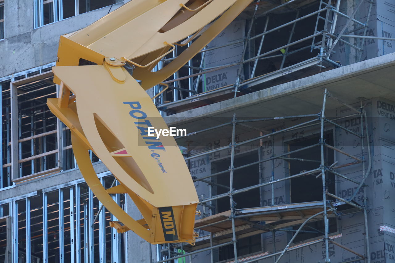 LOW ANGLE VIEW OF YELLOW SIGN BY BUILDING