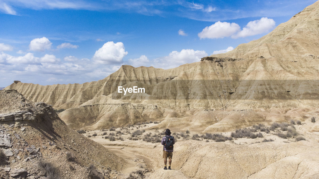 Panoramic view of the colored stone desert and traveler on his back walking on the rocks