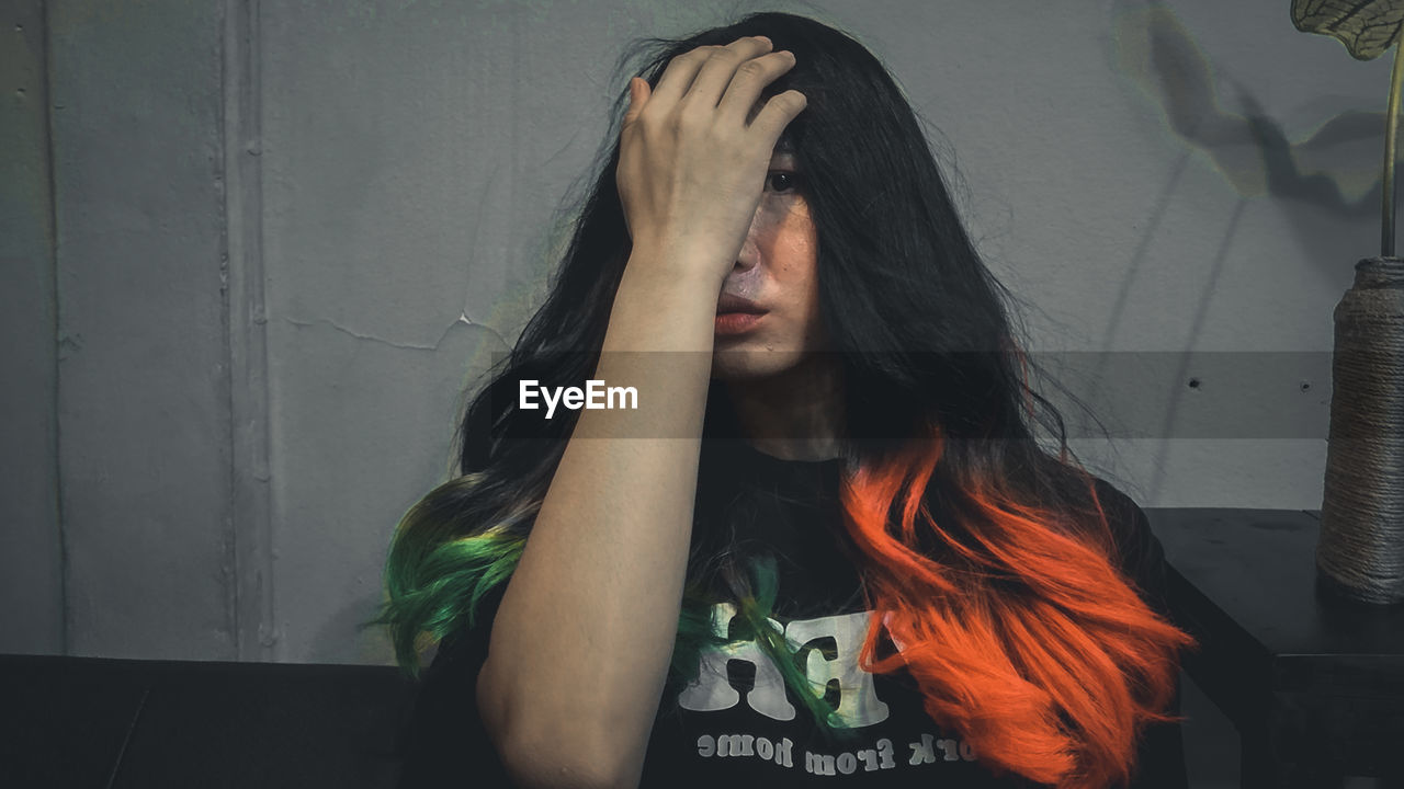 PORTRAIT OF YOUNG WOMAN AGAINST WALL IN ROOM