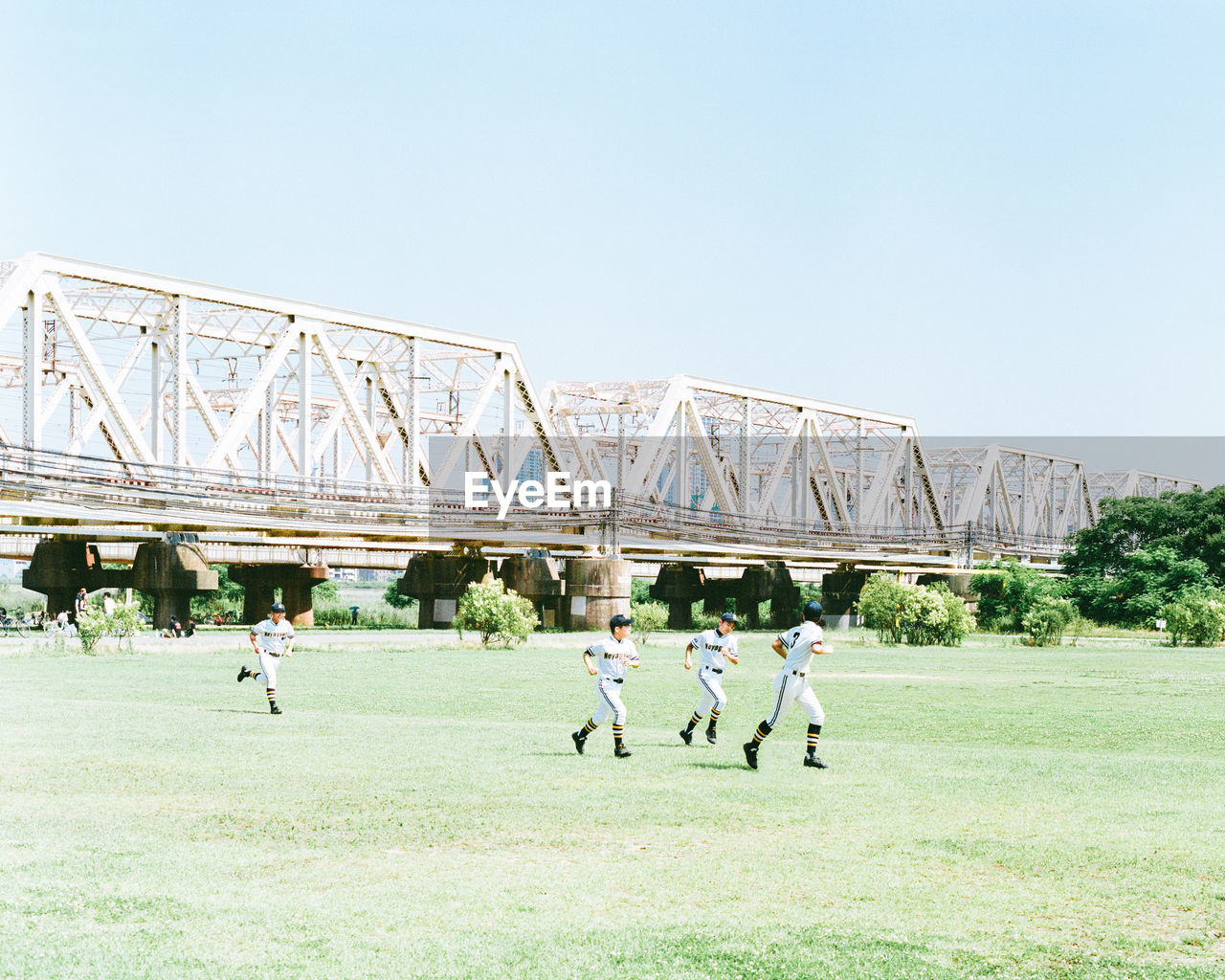 PEOPLE PLAYING SOCCER ON FIELD AGAINST SKY